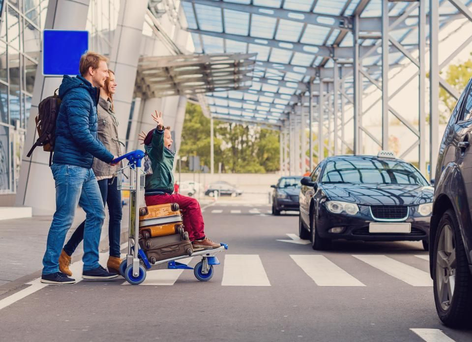 Familie kommt mit Gepäck aus einem Flughafen